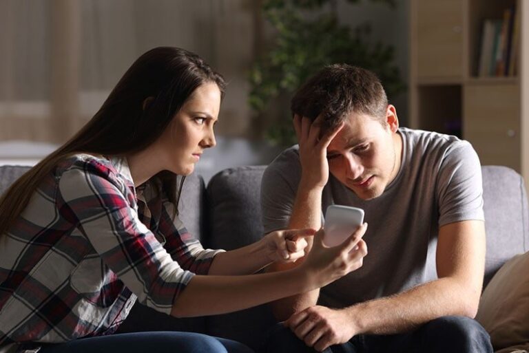 mujer enfadada enseñando el teléfono a su novio