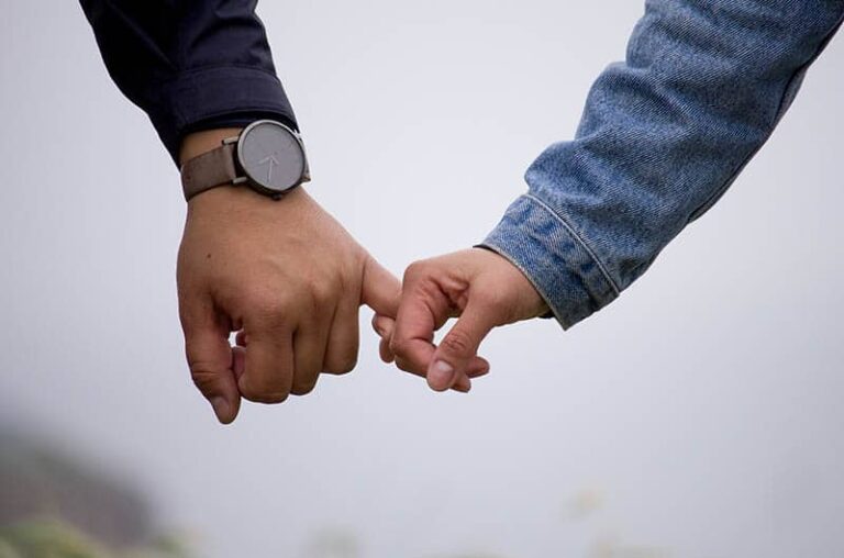 closeup photo man and woman holding pinky fingers
