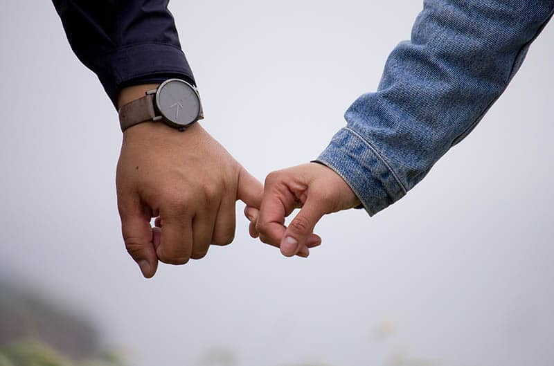 closeup photo man and woman holding pinky fingers