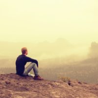 the man sits alone on the ground