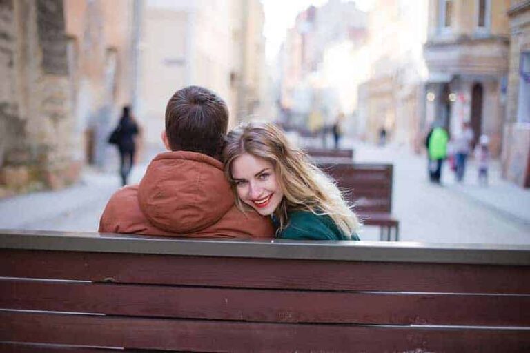 smiling woman sitting beside a man and looking back