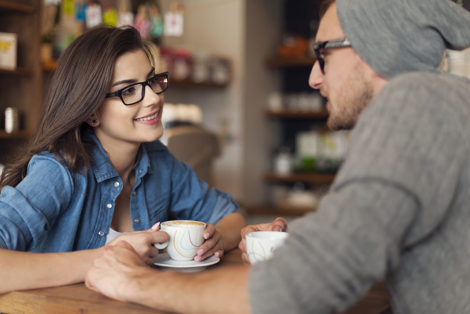 un uomo e una donna siedono l'uno di fronte all'altra a bere caffè e a parlare
