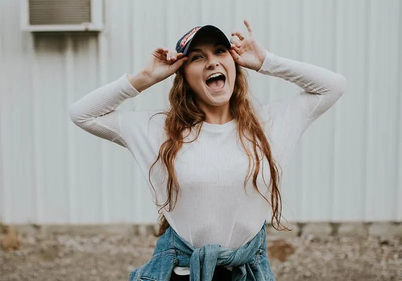 Happy young woman putting her cap on