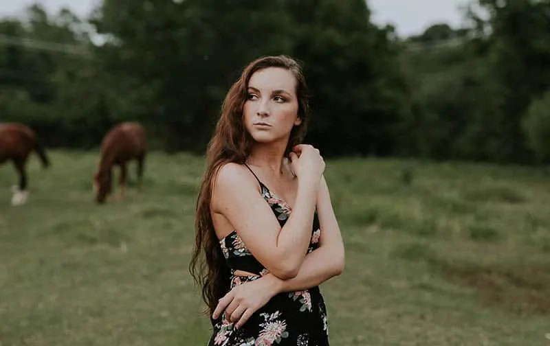 Young woman posing in dress in front of horses