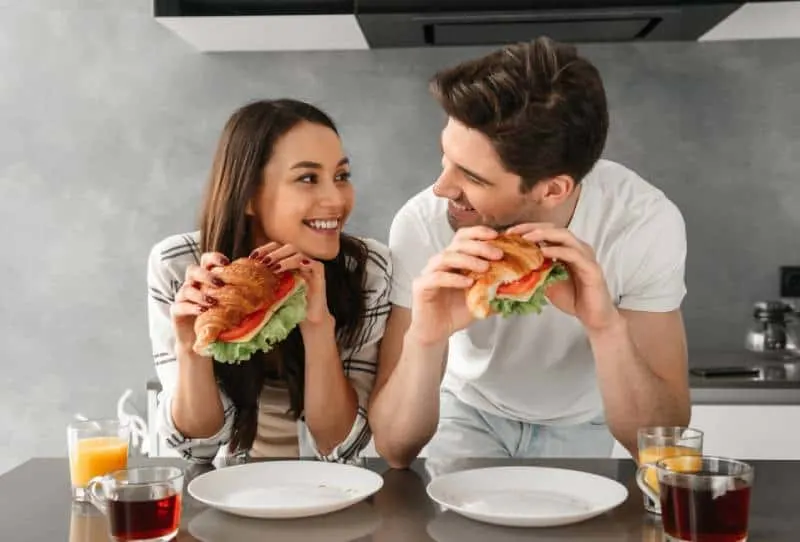 couple looking at each other and smiling while eating sandwiches
