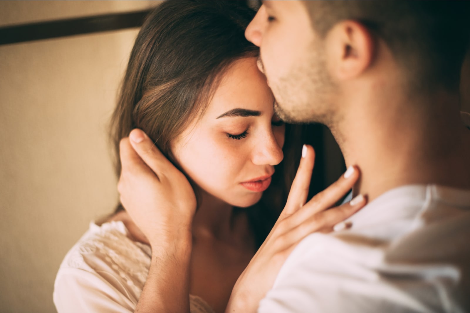 man kissing woman in the forehead