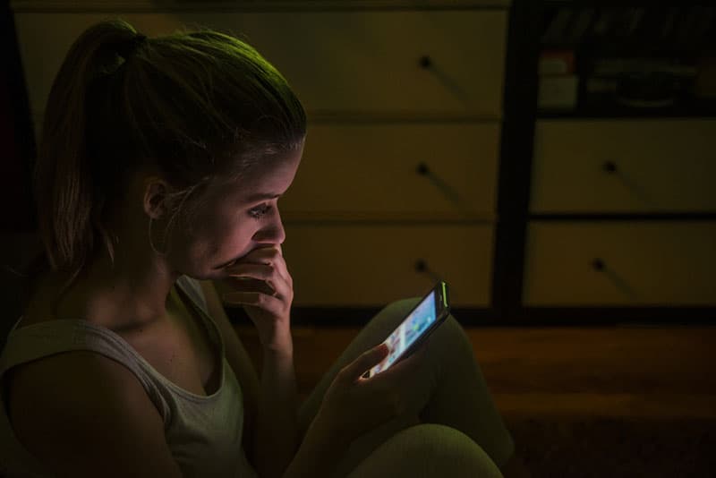 worried woman typing on her phone during night