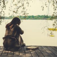 mujer solitaria sentada junto al río