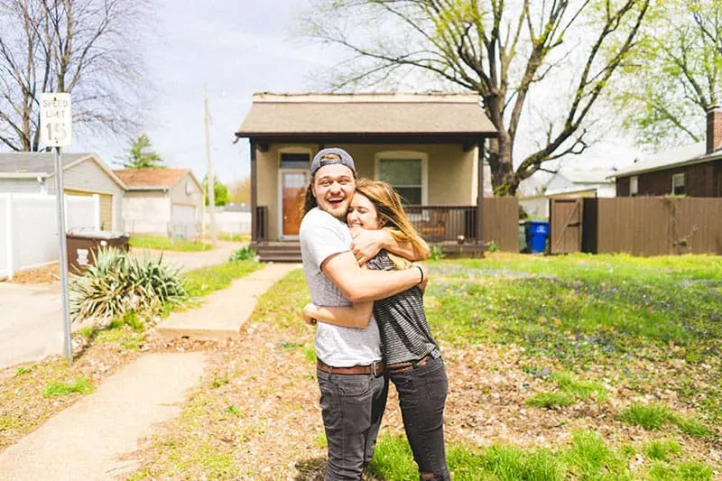 Happy couple hugging in front of a house
