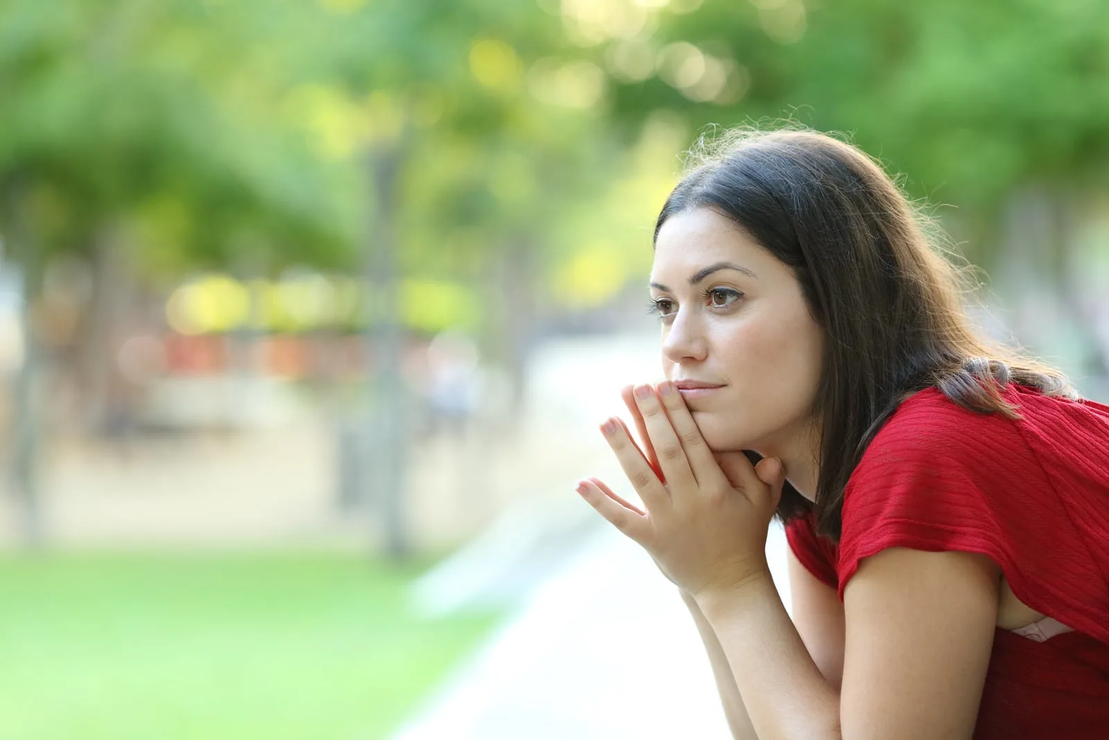 pensive woman sitting on a bench in a park