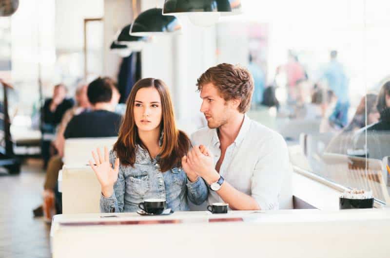 giovane coppia che flirta al bar mentre alla donna non piace