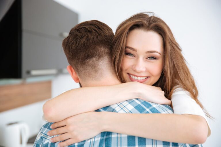 mujer sonriente abrazando fuertemente a un hombre