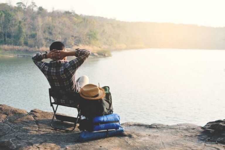 hombre sentado en la naturaleza frente al agua