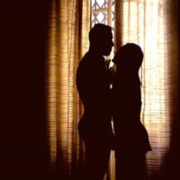 silhouette of couple standing beside window