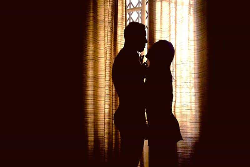 silhouette of couple standing beside window
