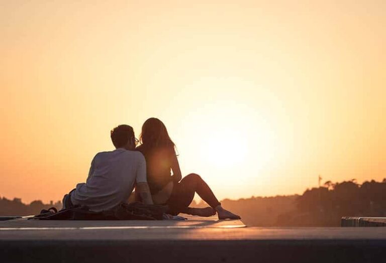 back view of couple facing sunset
