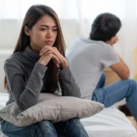 sad woman sitting with man on the bed