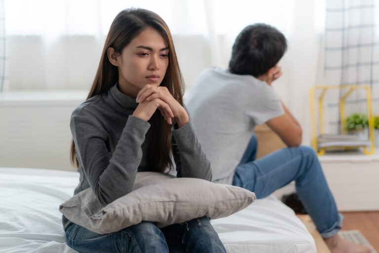 sad woman sitting with man on the bed