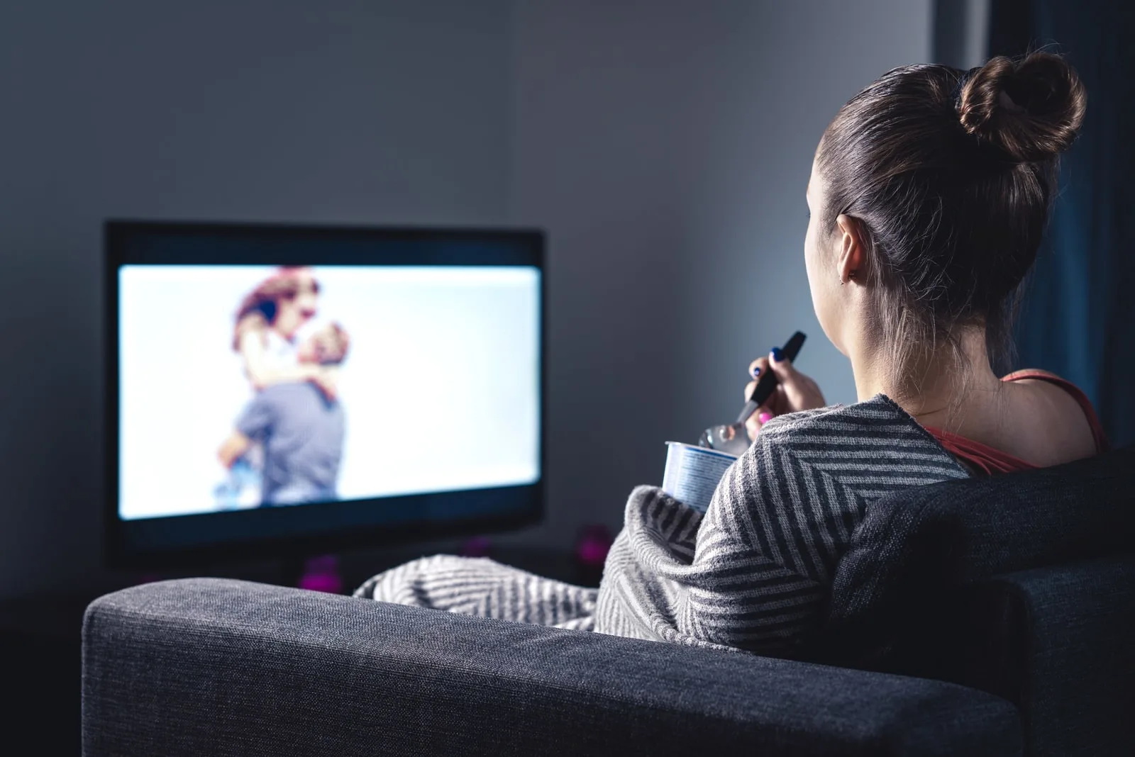 Woman watching romantic movie and eating ice cream
