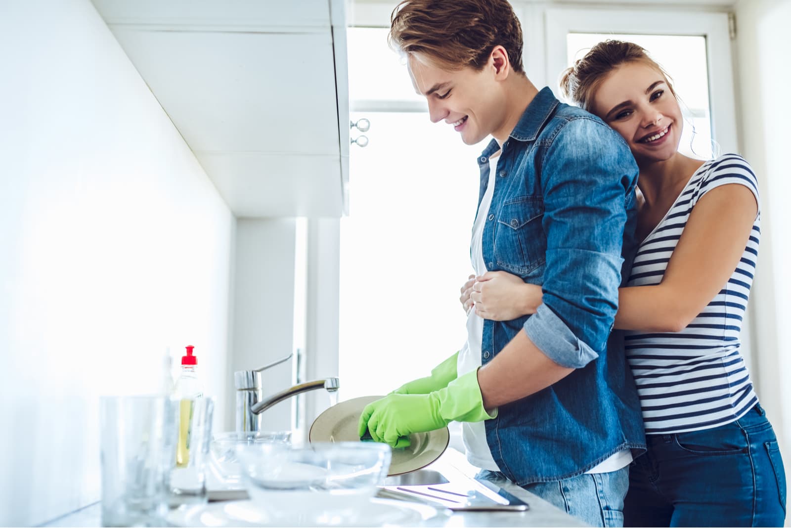 Young happy couple is washing dishes