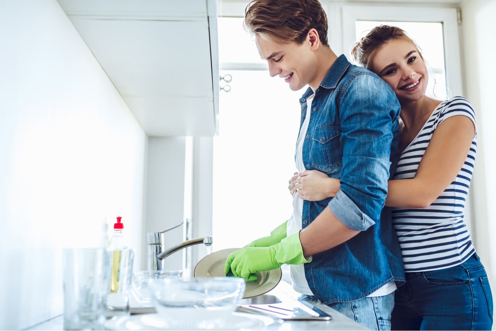 Jovem casal feliz está a lavar pratos