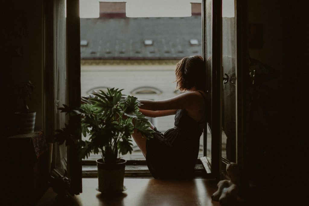 una chica triste sentada en la ventana