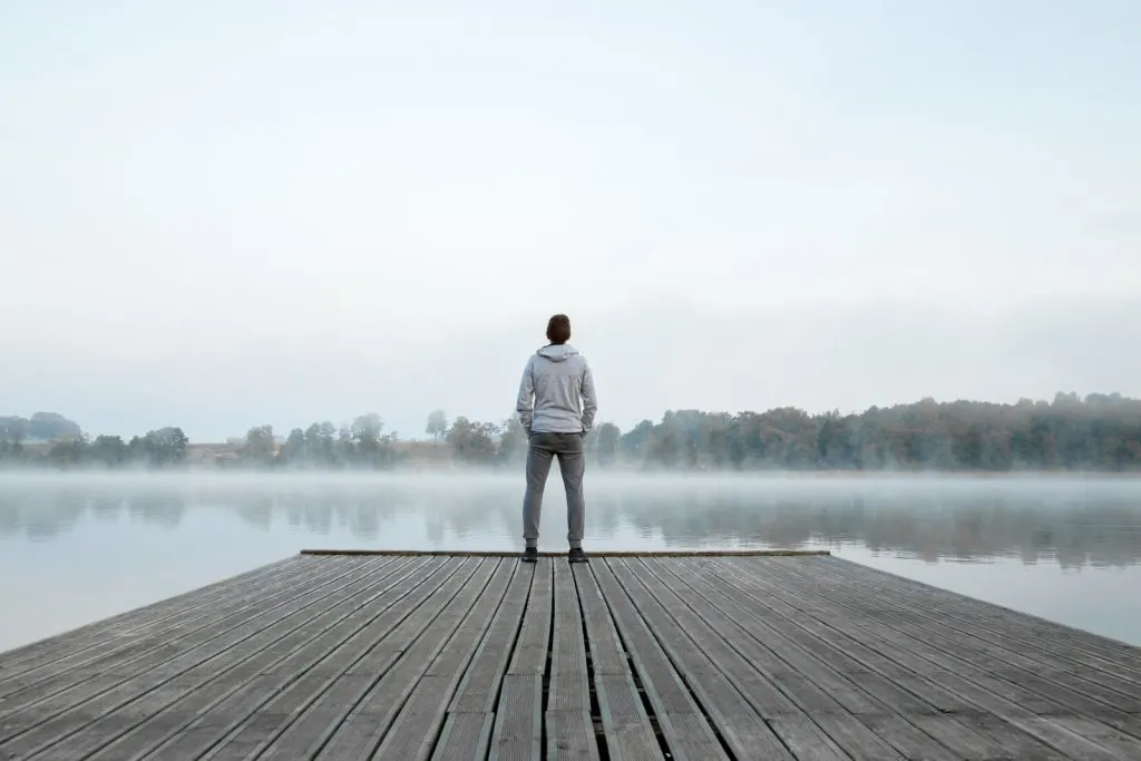 a young man standing alone on the dock