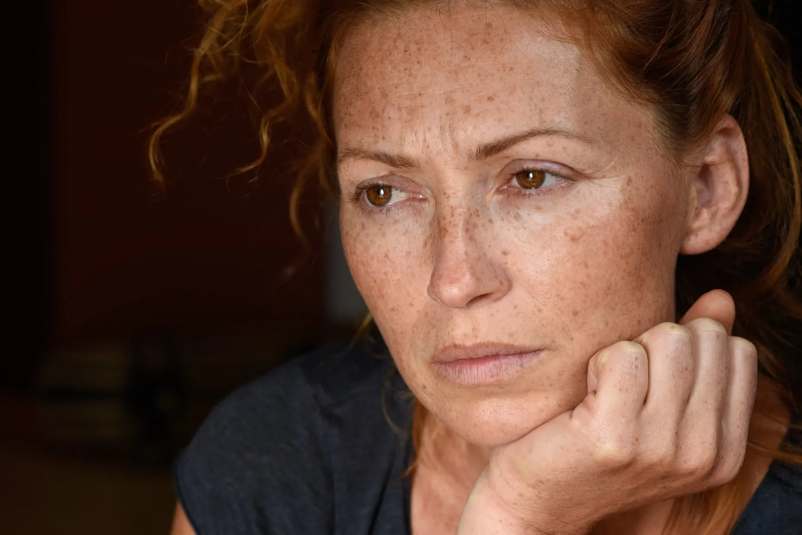 attractive red hair woman without makeup holding chin with hand