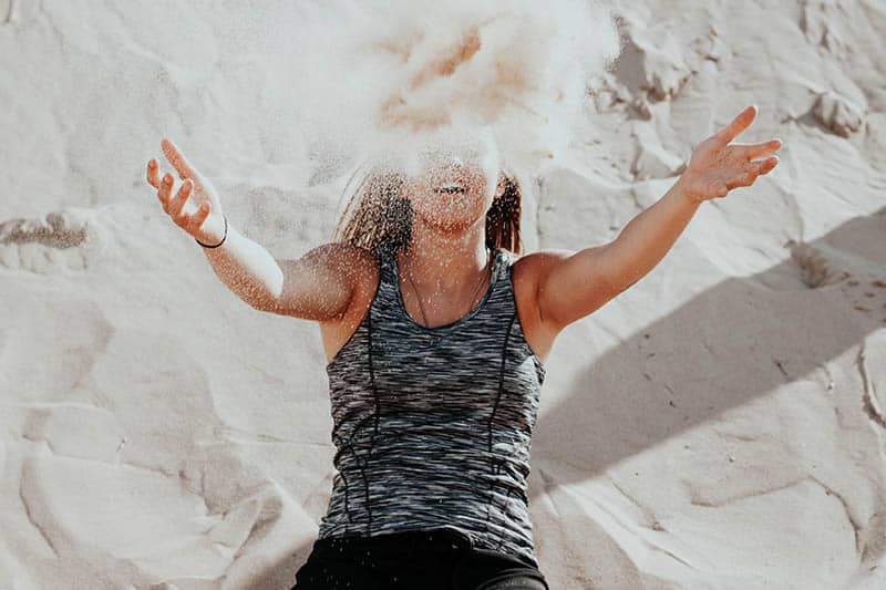 Ragazza che si getta addosso la sabbia della spiaggia