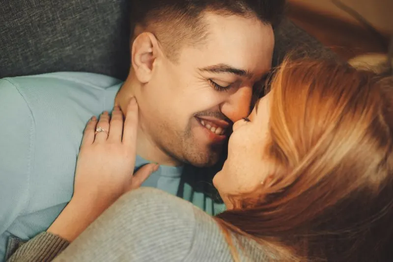 couple lying on couch kissing and smiling