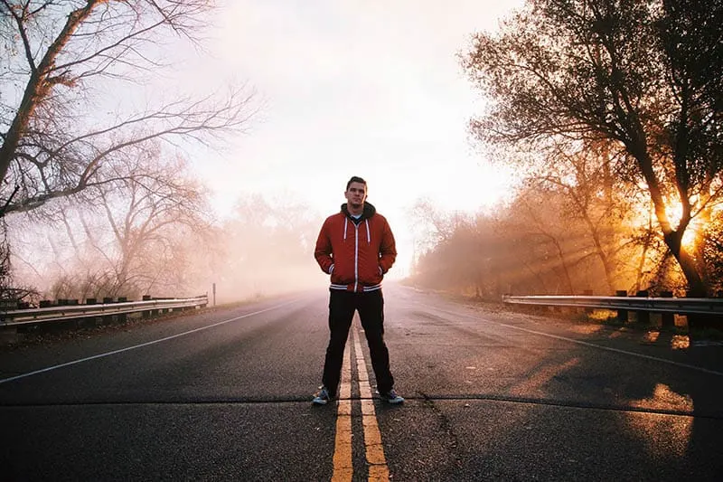 photo of man standing on the road during daytime