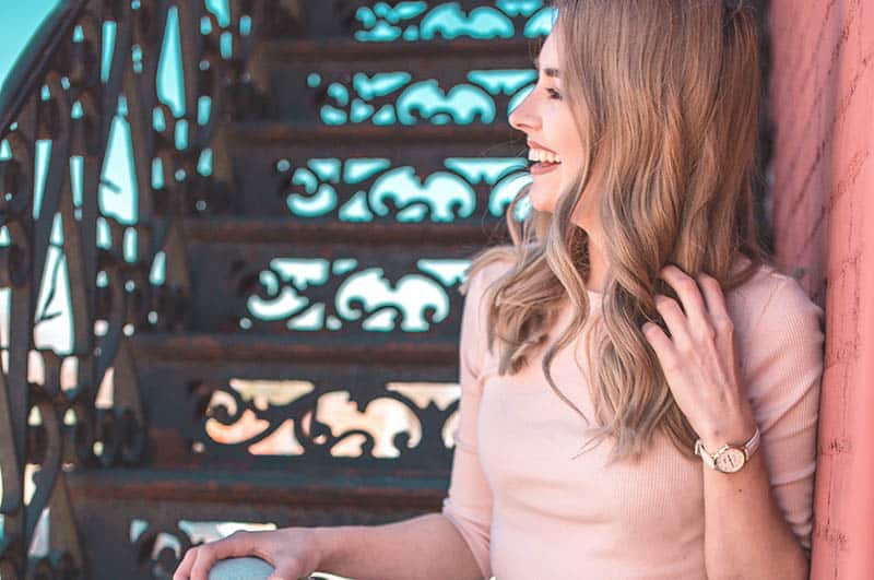 side view of smiling blonde woman leaning on the wall