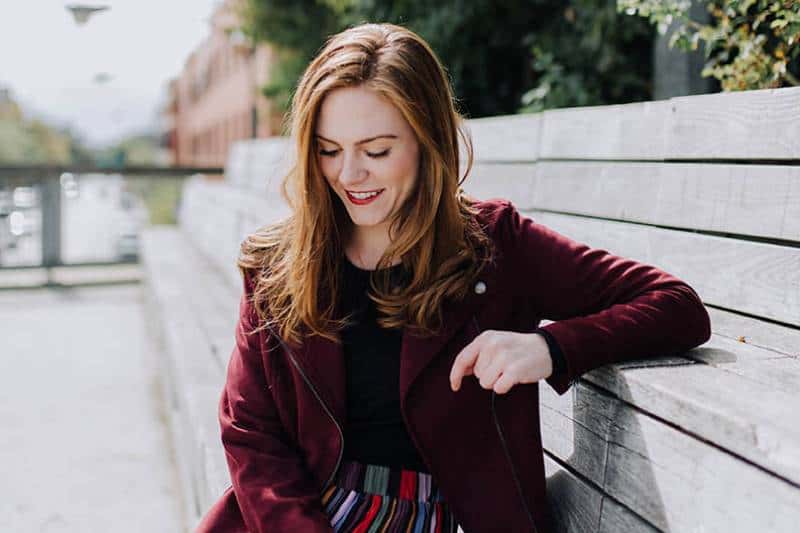 smiling woman looks down while sitting outside