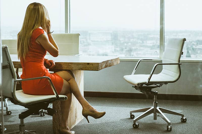 woman in dress with crossed legs sitting on chair