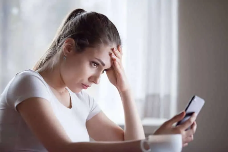 worried woman looking at her phone at home