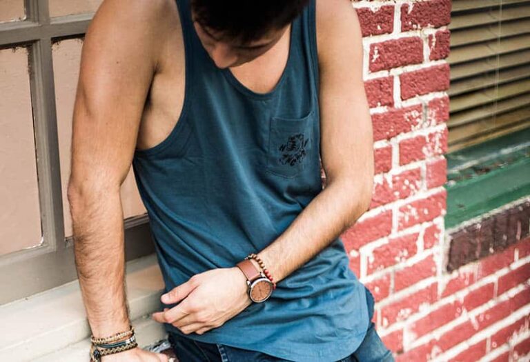 man in shirt looking his bracelets