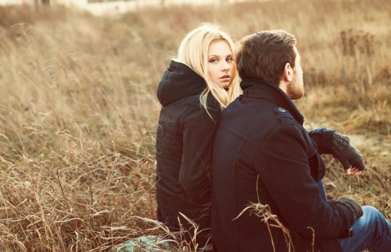 man and woman sitting in brown field