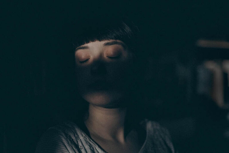 woman's face with closed eyes in the dark