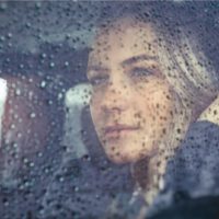 Mulher bonita e triste sentada no carro em tempo de chuva,