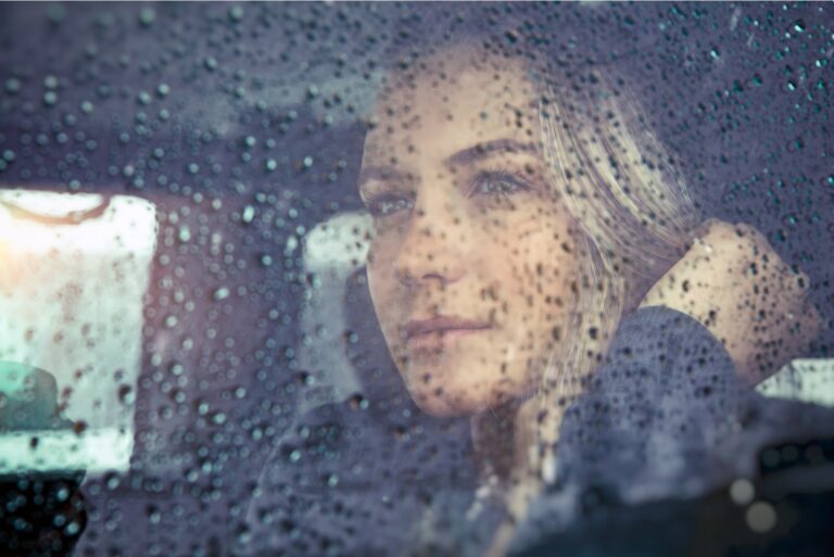 beautiful sad woman sitting in the car in rainy weather,