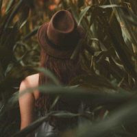 vista posteriore di donna con cappello circondata dalla natura