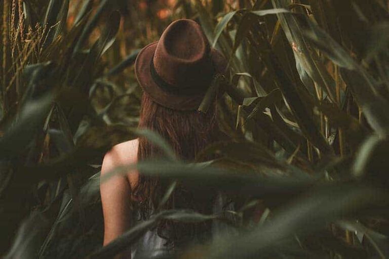 back view of woman wearing hat surround by nature