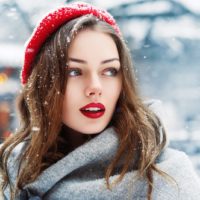 una bellezza con un berretto rosso in piedi fuori nella neve