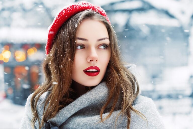 a beauty with a red cap standing outside in the snow