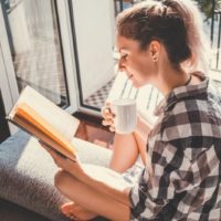 the woman drinks coffee and reads a book