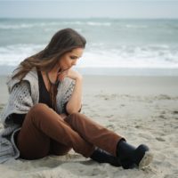 donna triste seduta sulla spiaggia