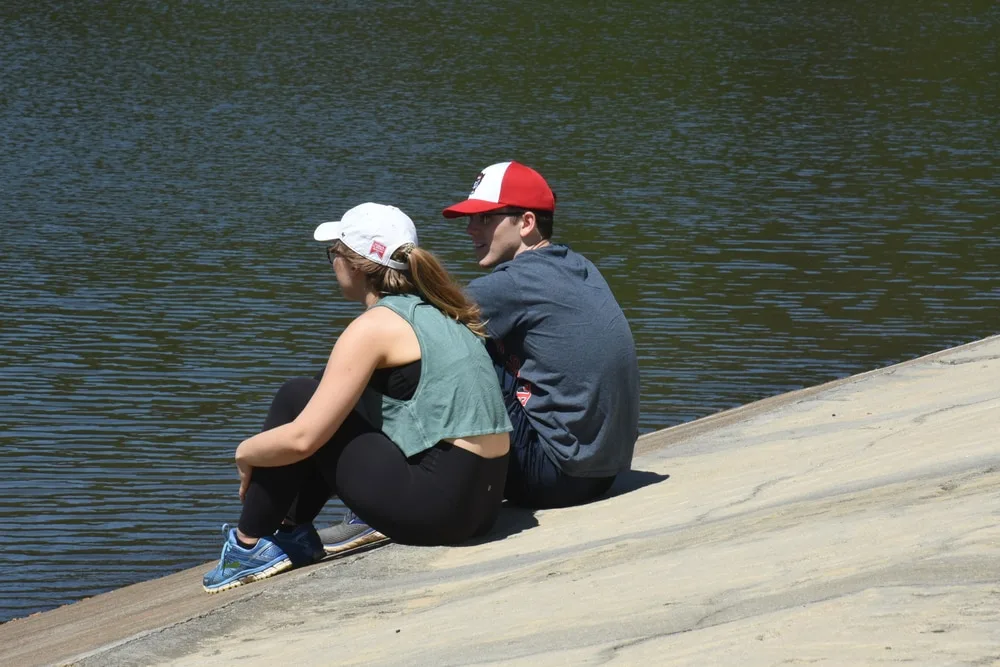 a loving couple sitting on a concrete shore and talking