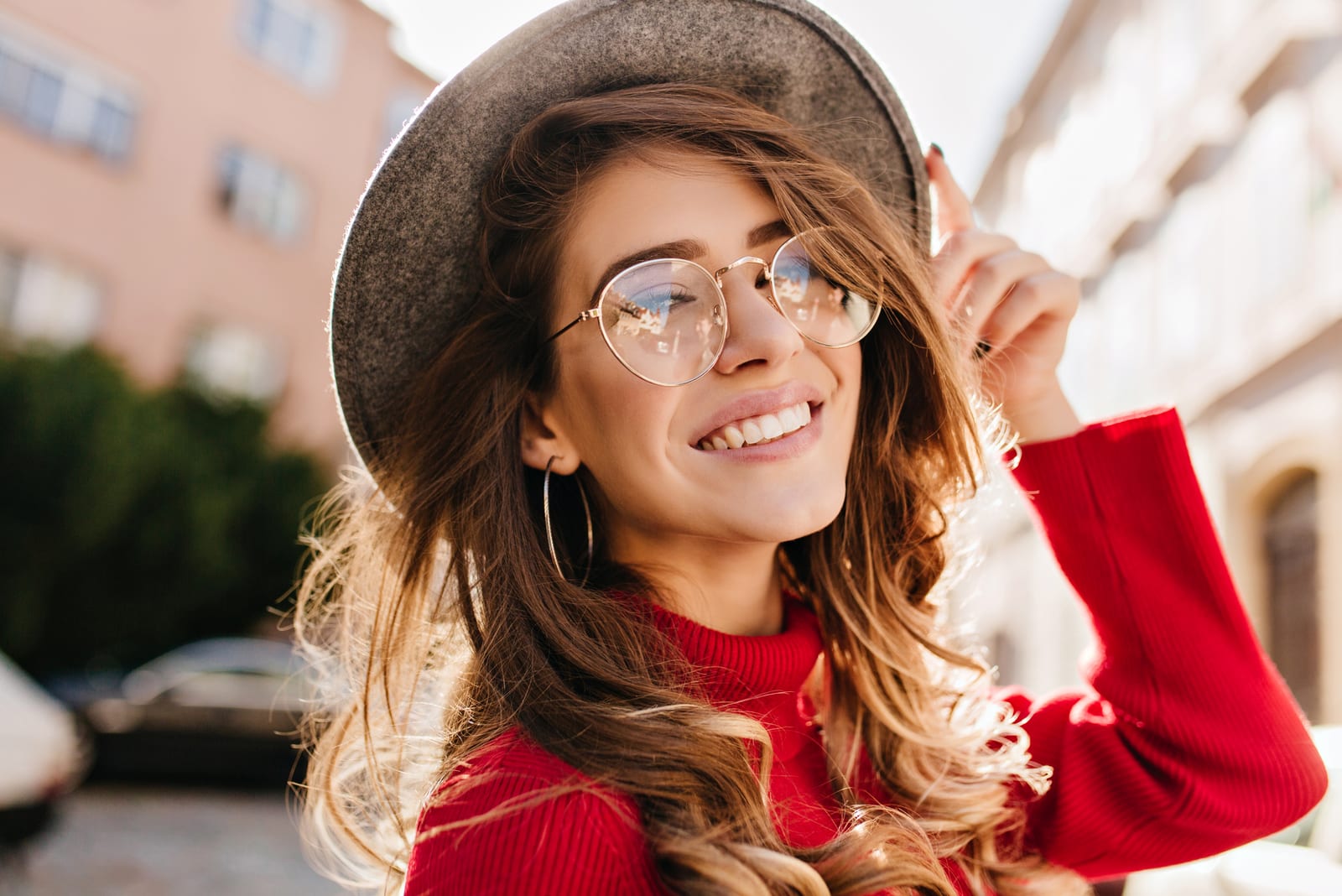 a woman with glasses and a hat on her head laughs