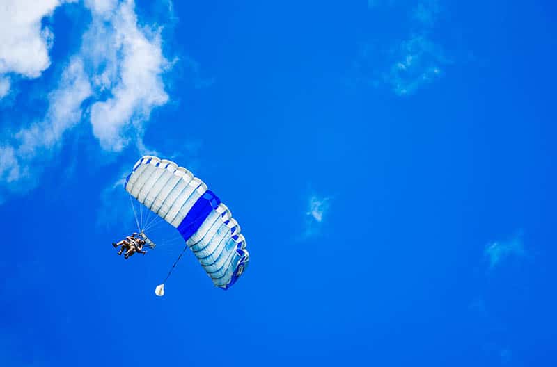 Due persone che fanno parapendio con il cielo azzurro sullo sfondo