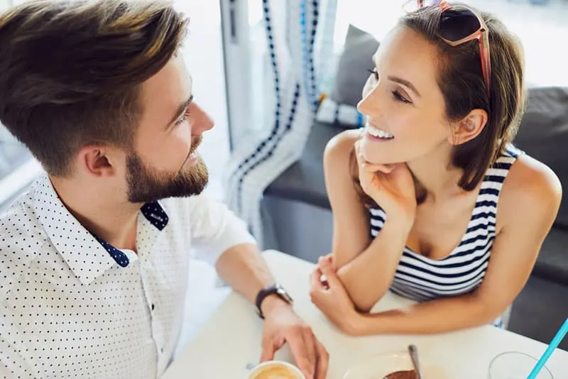 smiling couple looking at each other while sitting on table